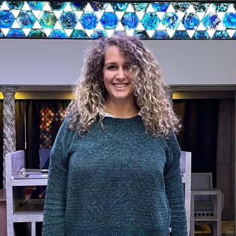 Tori Greene standing in the sanctuary beneath a stained-glass band of Stars of David